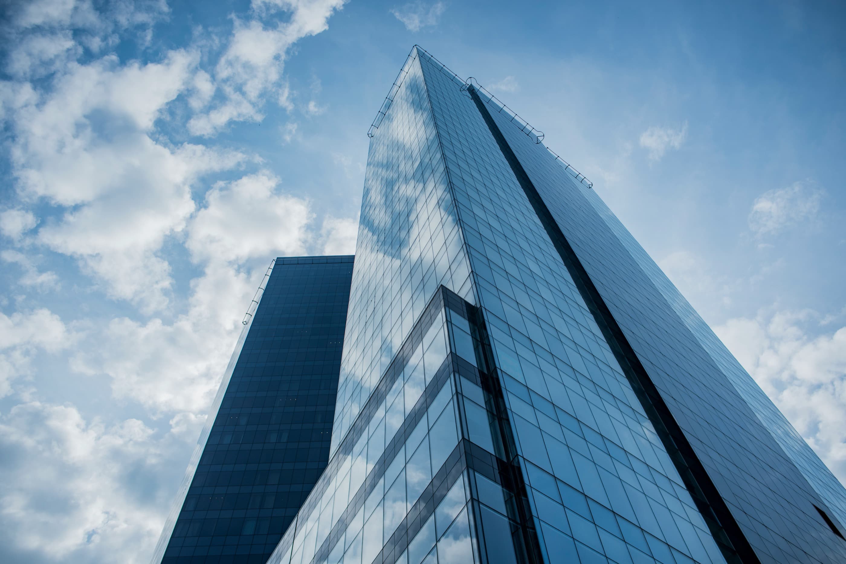 Looking up at glass skyscrapers against a blue sky